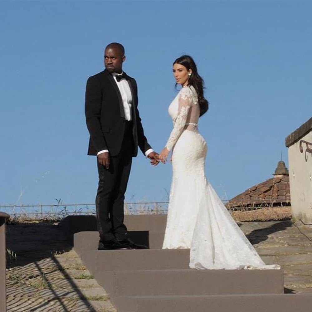 Kim Kardashian and Kanye West posing in wedding attire on stone steps.