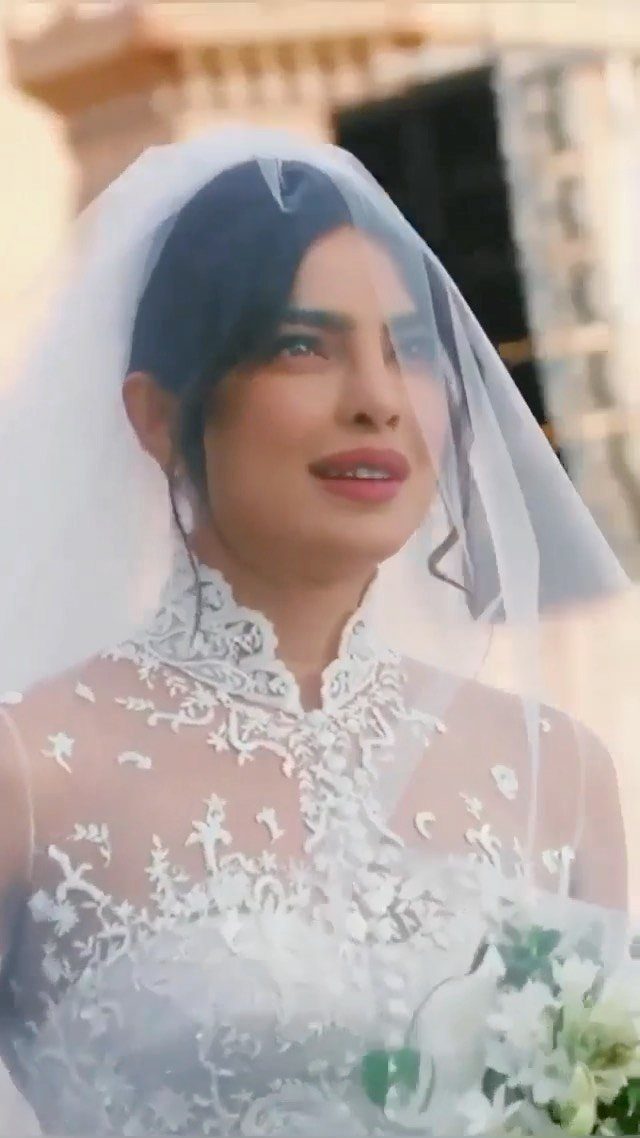 Priyanka Chopra in a high-neck lace wedding dress and sheer white bridal veil.