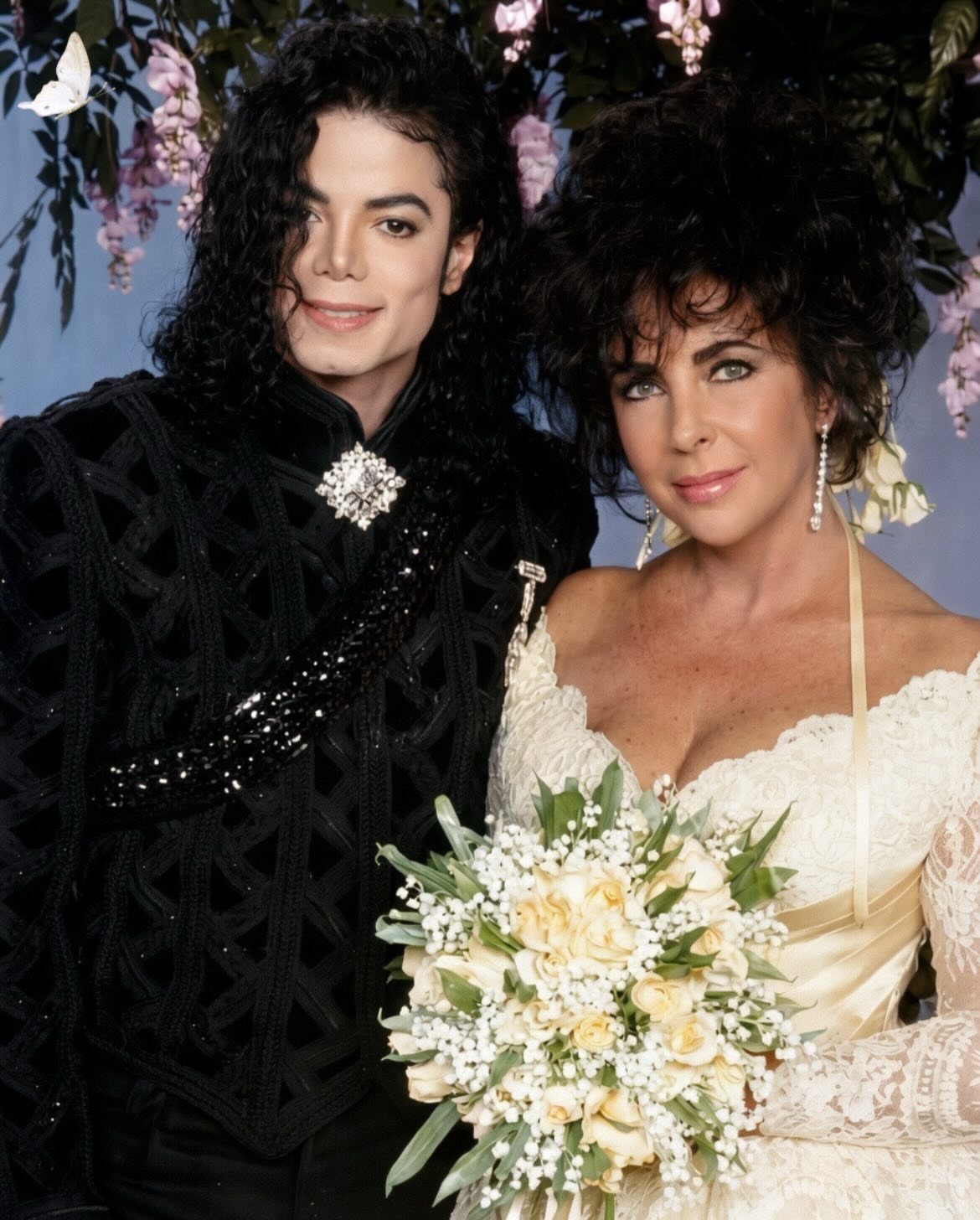 Michael Jackson and Lisa Marie Presley posing in wedding attire with white roses.
