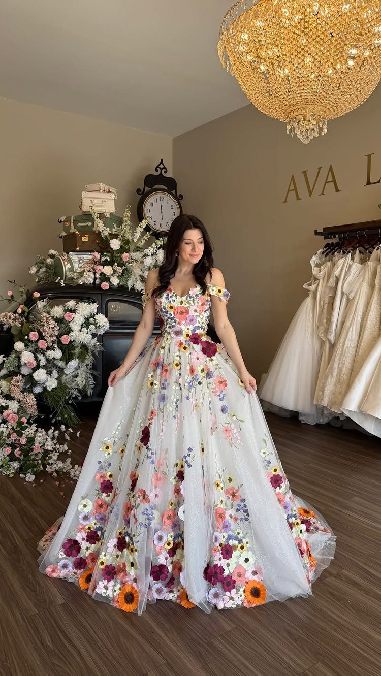Woman in a white bridal gown with colorful floral embroidery in a boutique