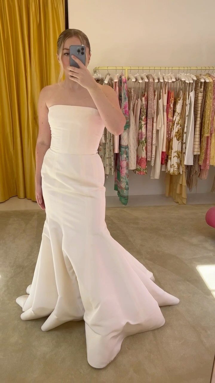 Woman in a strapless white architectural bridal gown with a flared structured skirt.