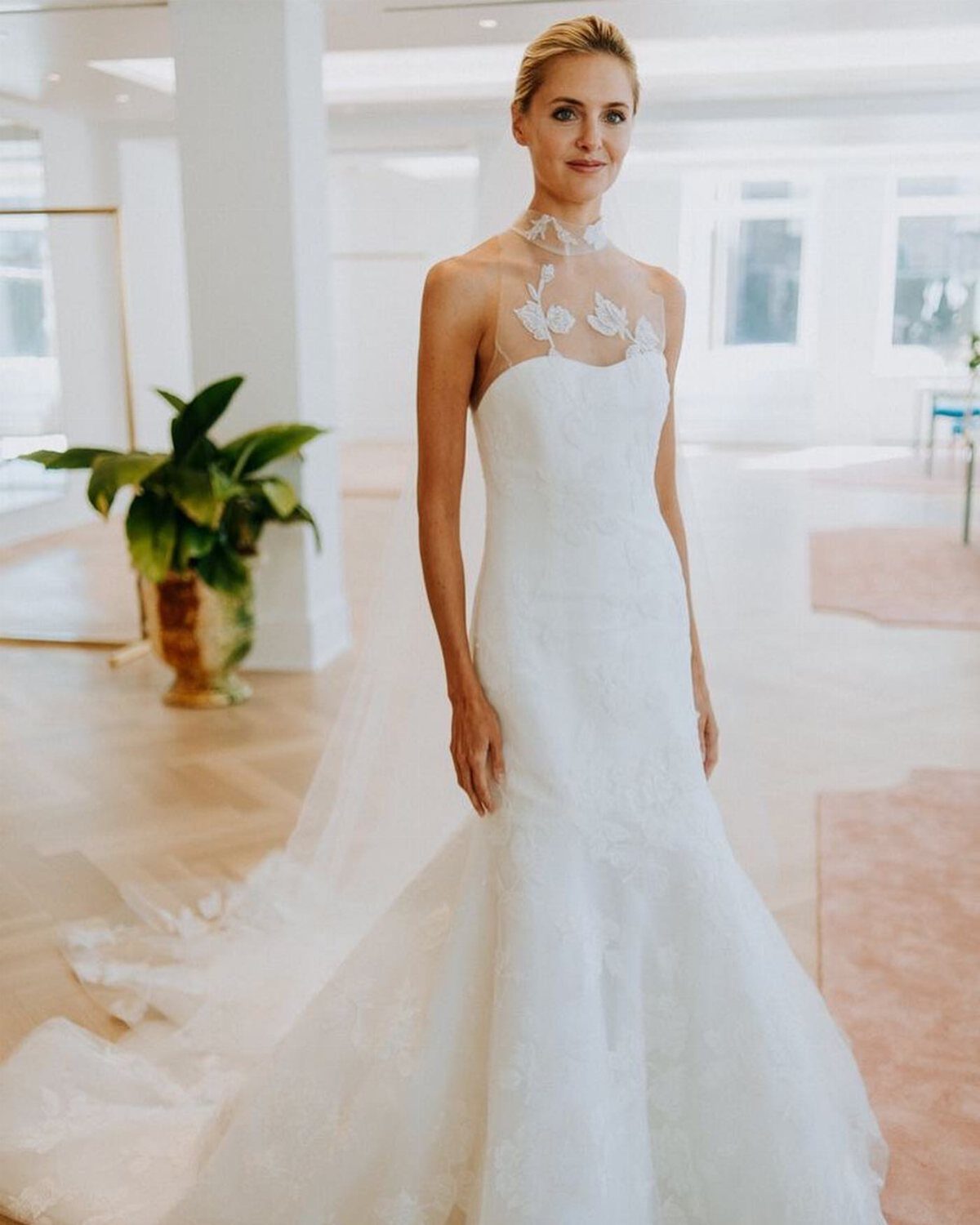 Woman in a white bridal gown with a high lace neckline in a bright room