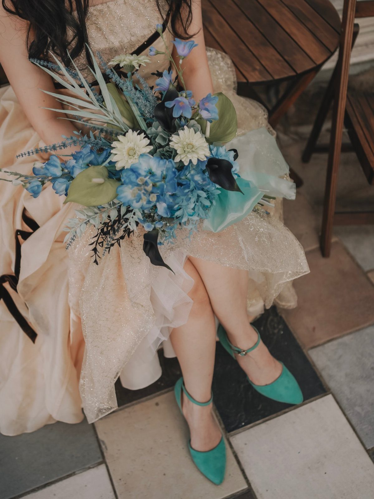 Champagne shimmering gown with black ribbons and a blue floral bouquet