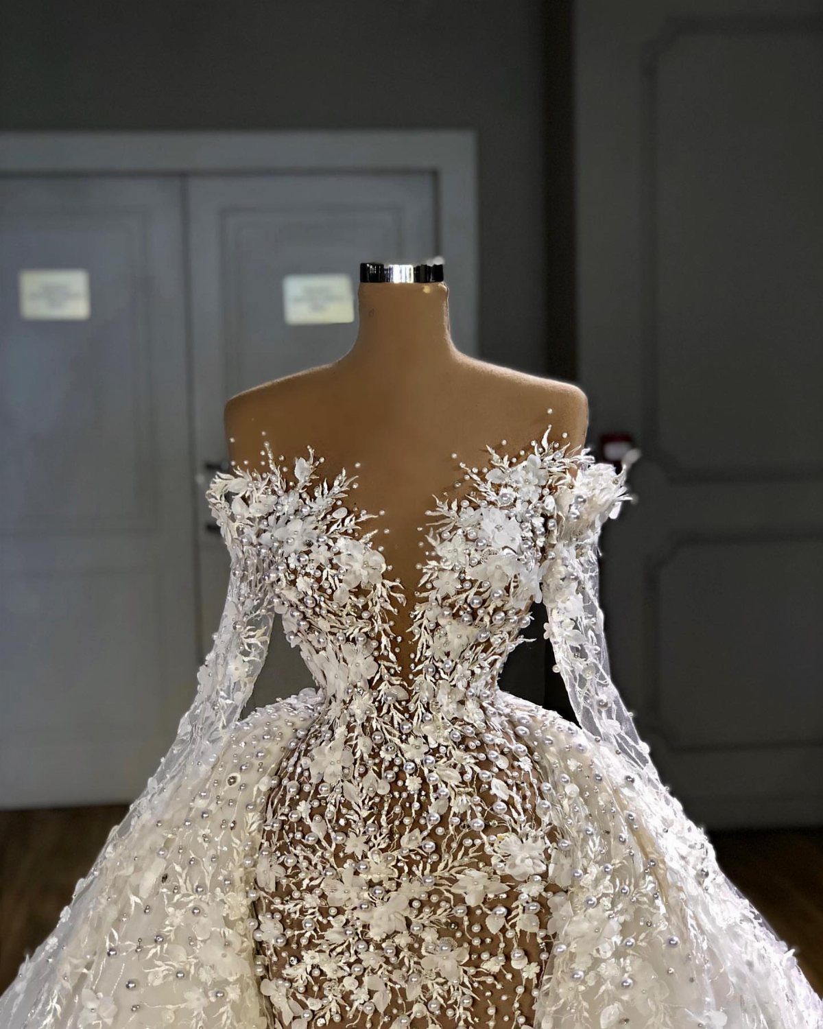 Ornate white ball gown wedding dress with floral lace on a mannequin.