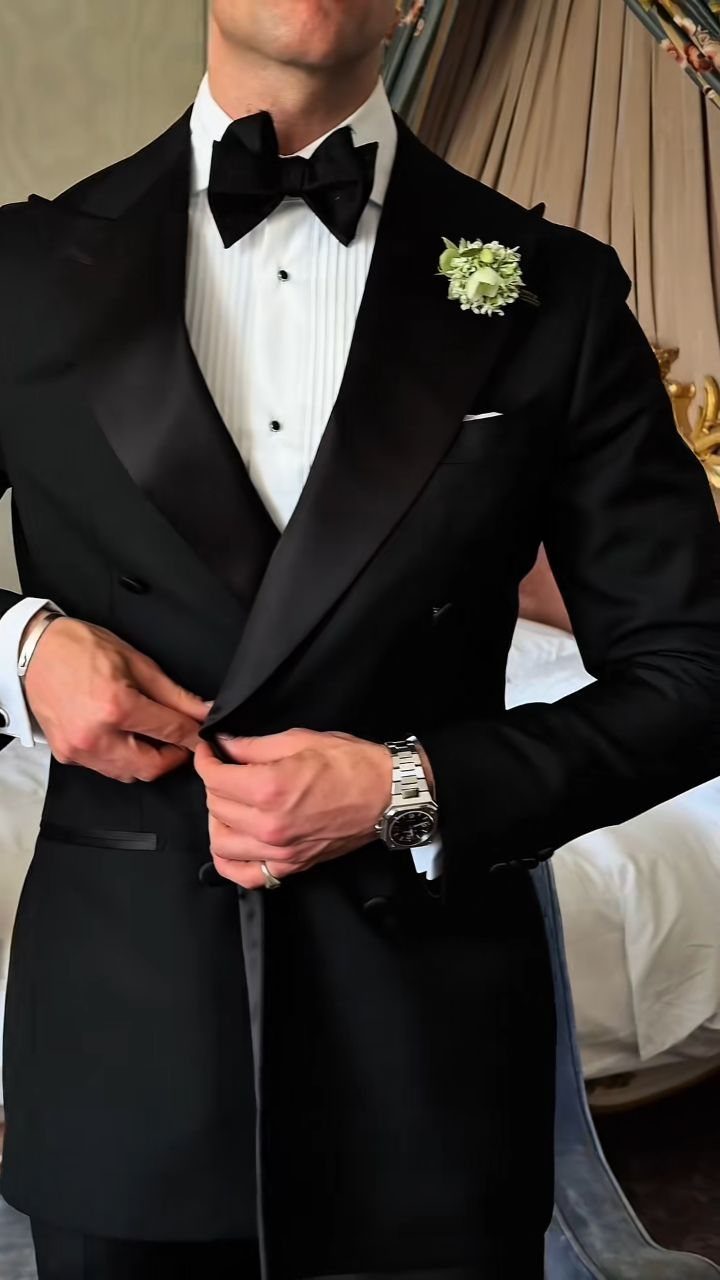 Man in a black tuxedo with a bow tie and white floral boutonniere.