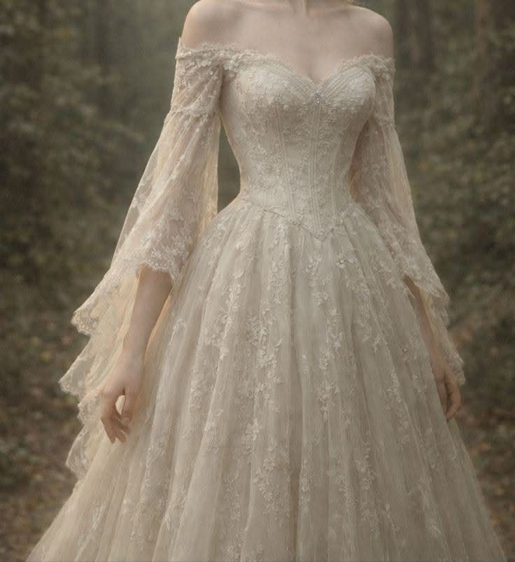 Cream lace wedding dress with flowing bell sleeves in a misty forest setting