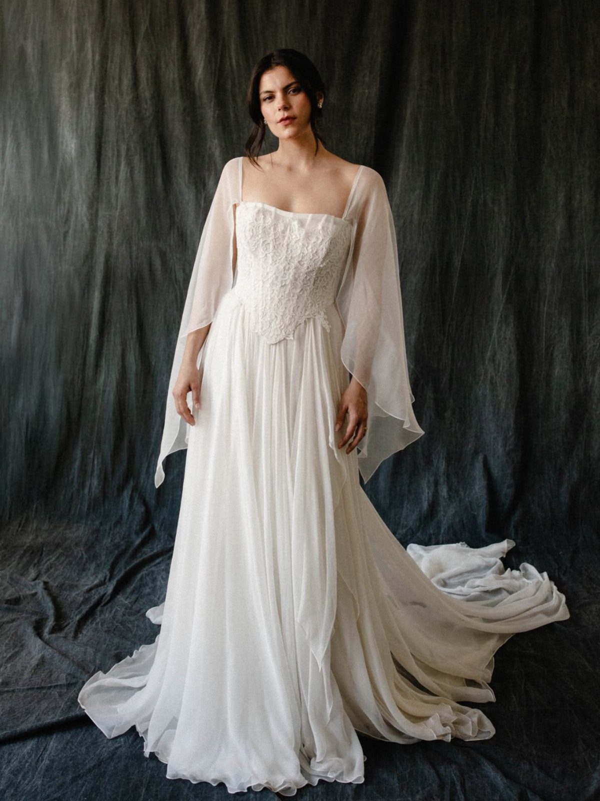 Woman in a white flowing chiffon gown with oversized floor-length bell sleeves.