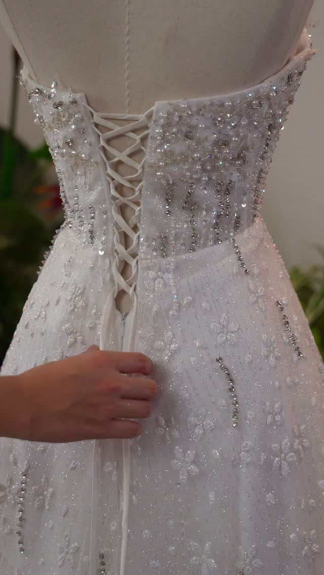 White wedding dress with lace-up back and beaded floral embroidery on a mannequin