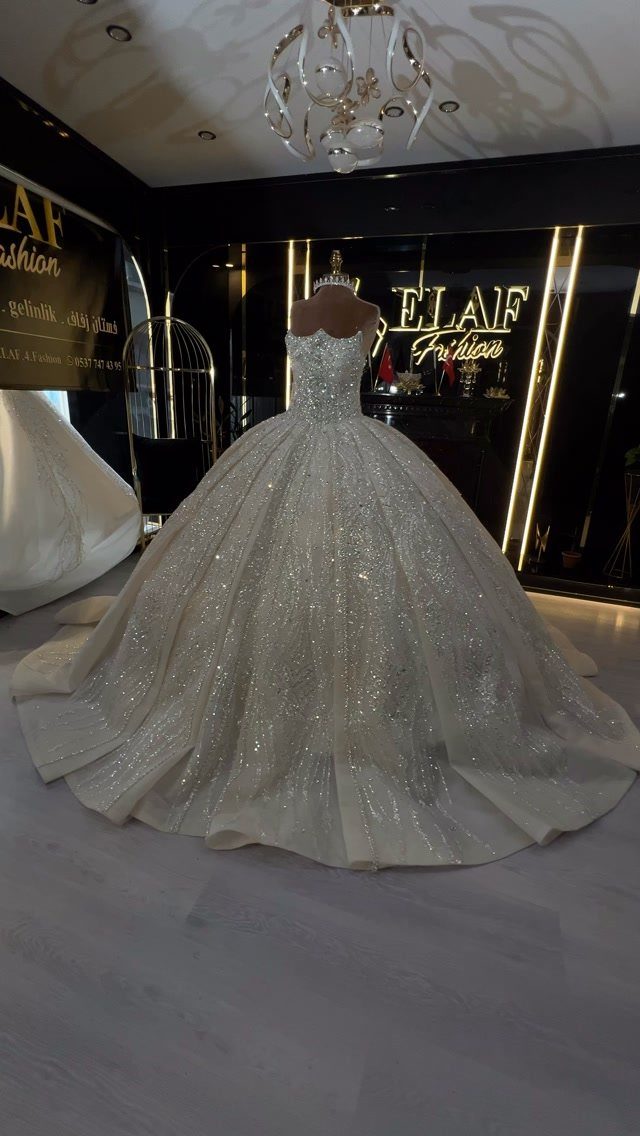 Sparkling white ballgown wedding dress on a mannequin in a bridal boutique setting.
