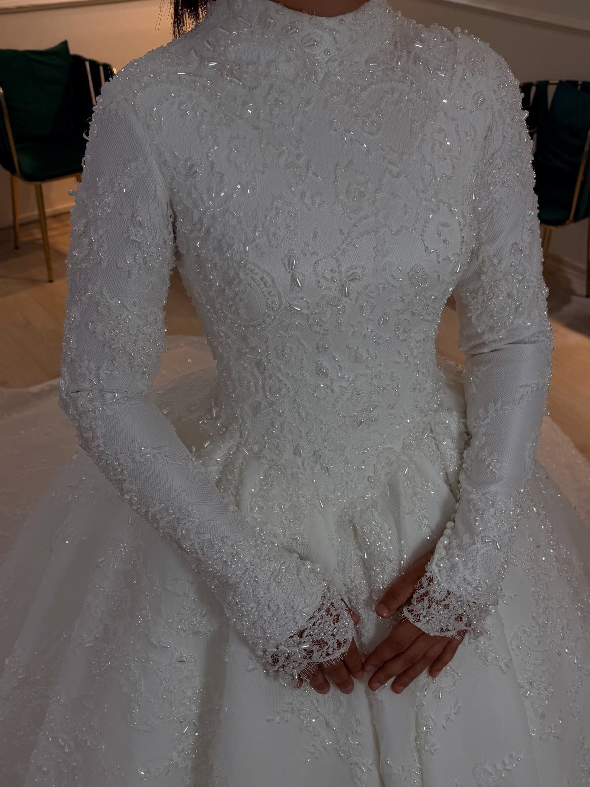White wedding dress with high neck, long lace sleeves, and beaded floral embroidery.