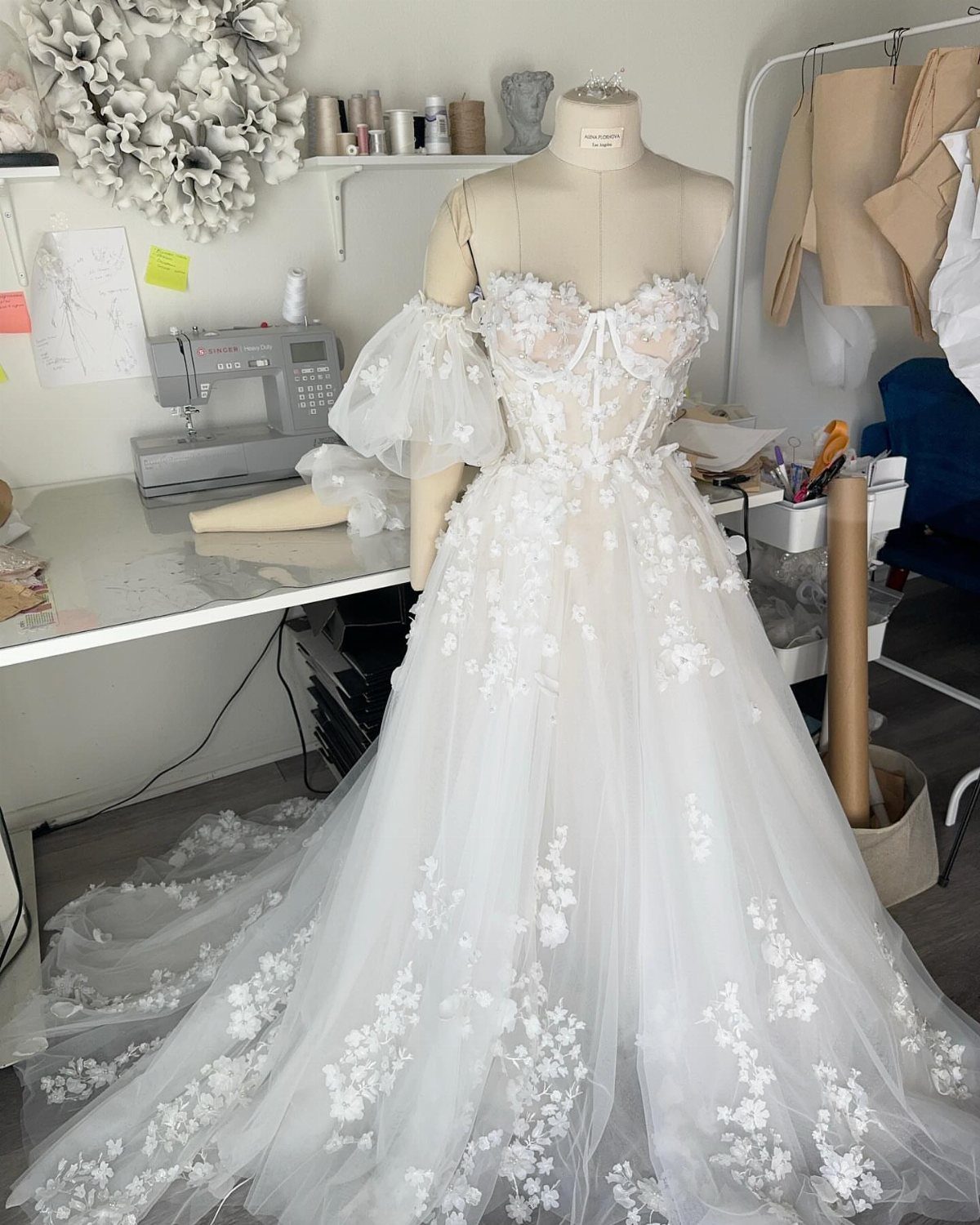 White floral lace wedding dress with puffy sleeves on a dressmaker mannequin