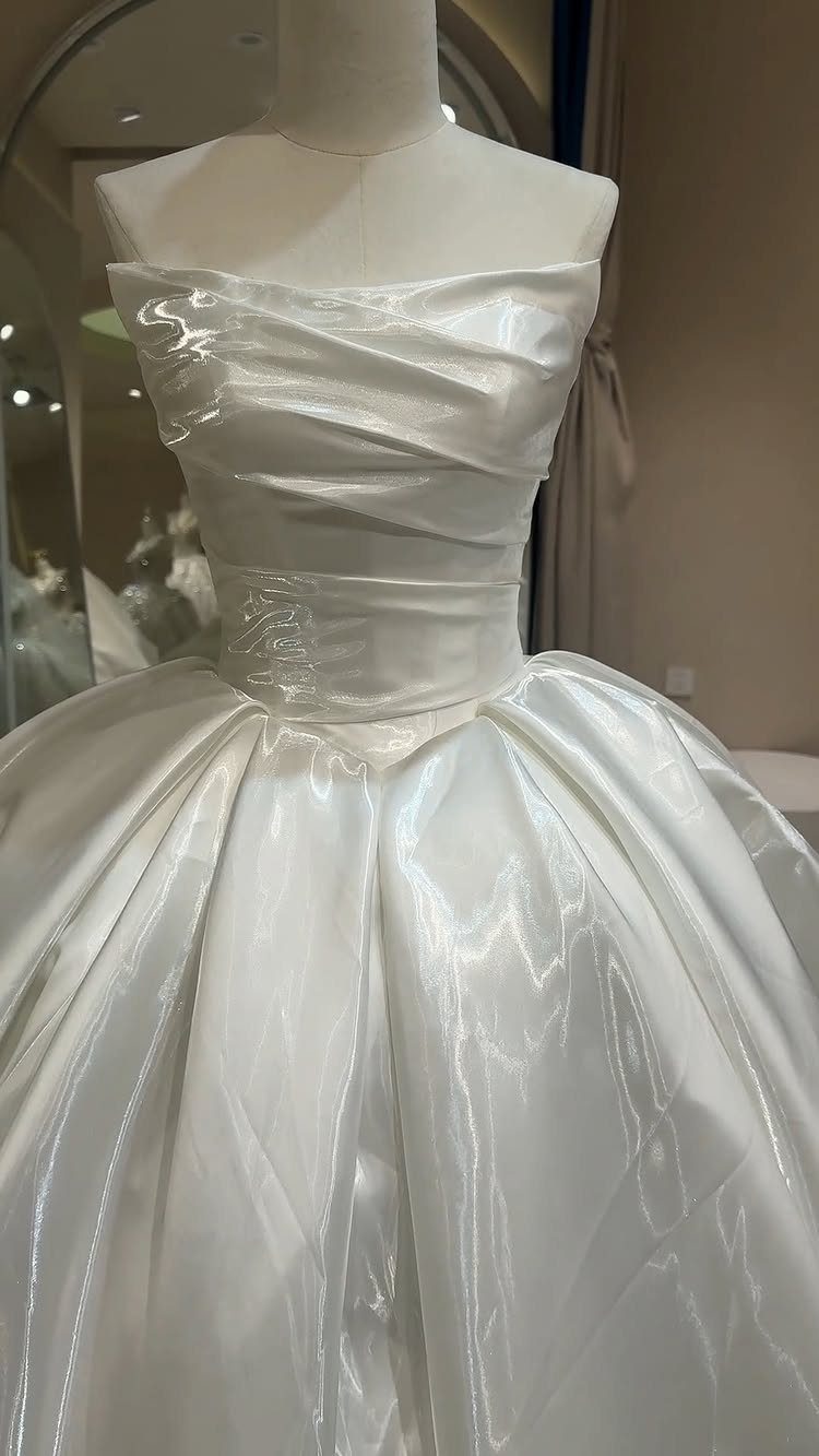 White satin wedding dress with ruched bodice and full skirt on a mannequin