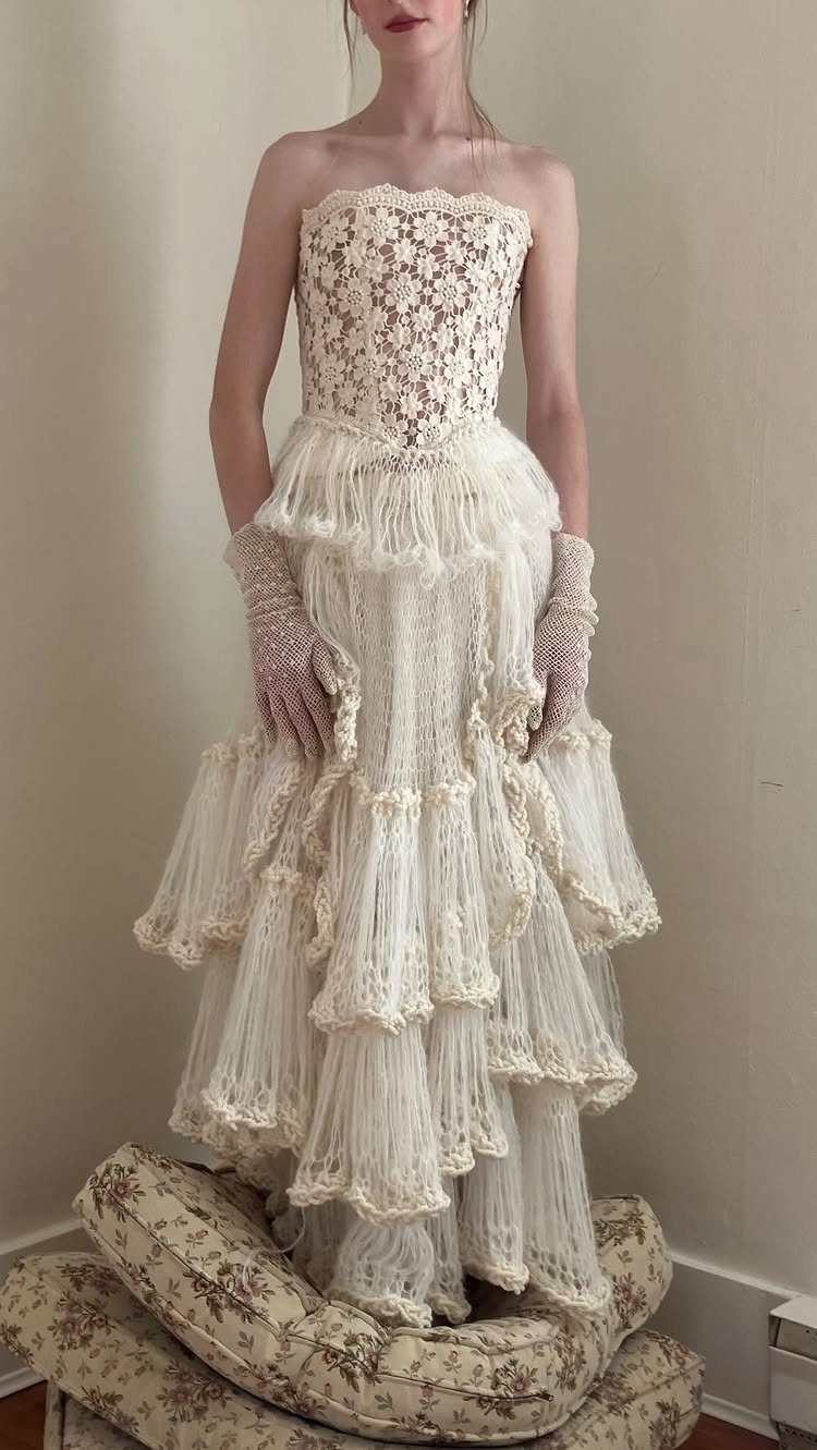 Woman wearing a strapless cream lace wedding dress with tiered ruffles and lace gloves.
