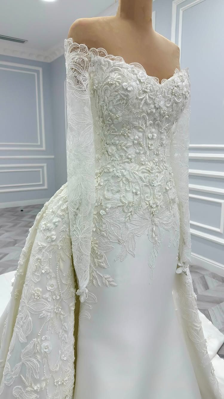 White off-the-shoulder wedding gown with intricate lace bodice and smooth silk skirt.