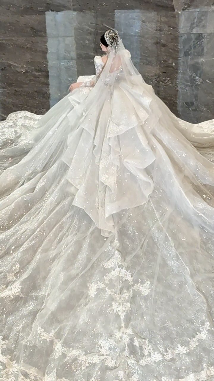 Woman in a voluminous white sparkling wedding dress with a long lace train.