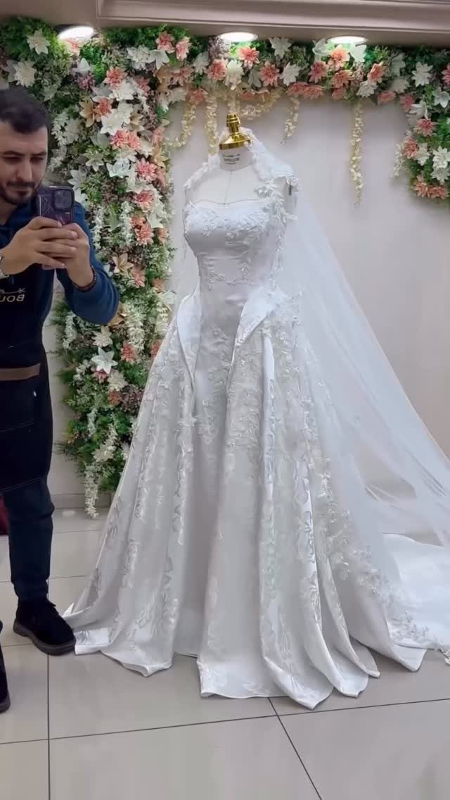White floral jacquard wedding dress on a mannequin with a long flowing veil.