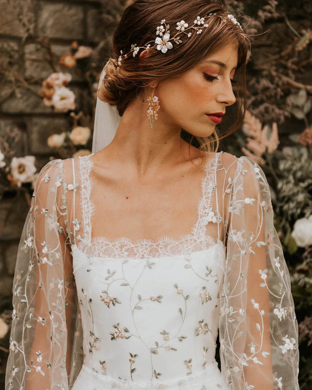Woman in a white wedding dress with wildflower embroidery and a floral headpiece.