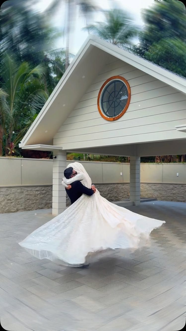 Groom lifting bride in a white wedding dress outdoors in front of a building
