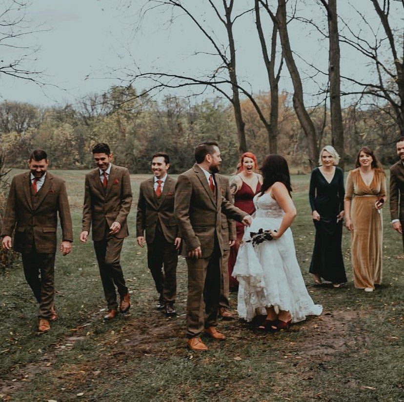 Groom and groomsmen in brown tweed suits walking with a bride outdoors.