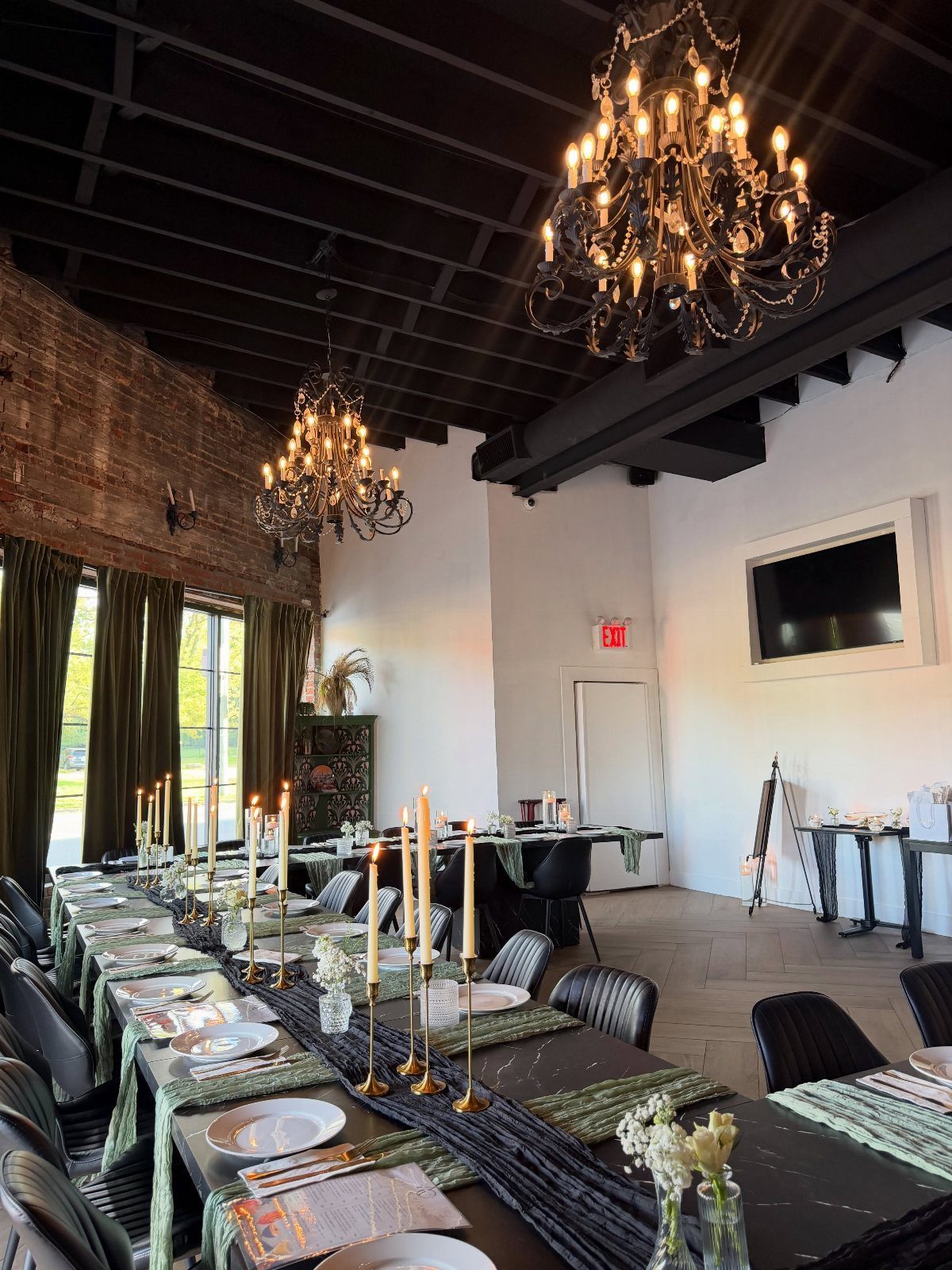 Elegant restaurant dining table set with black linens, gold candle holders, and chandeliers.