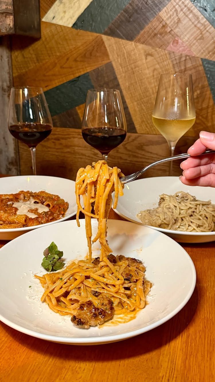 Pasta dishes and glasses of red and white wine on a wooden table