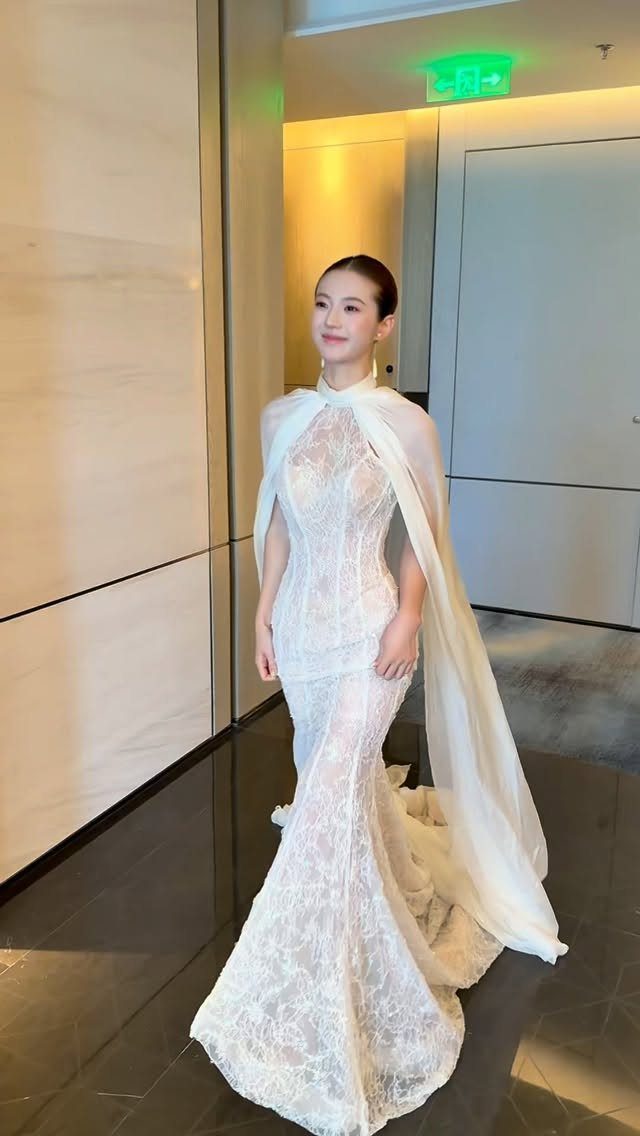 Woman in a white lace halter mermaid wedding dress with a sheer cape.