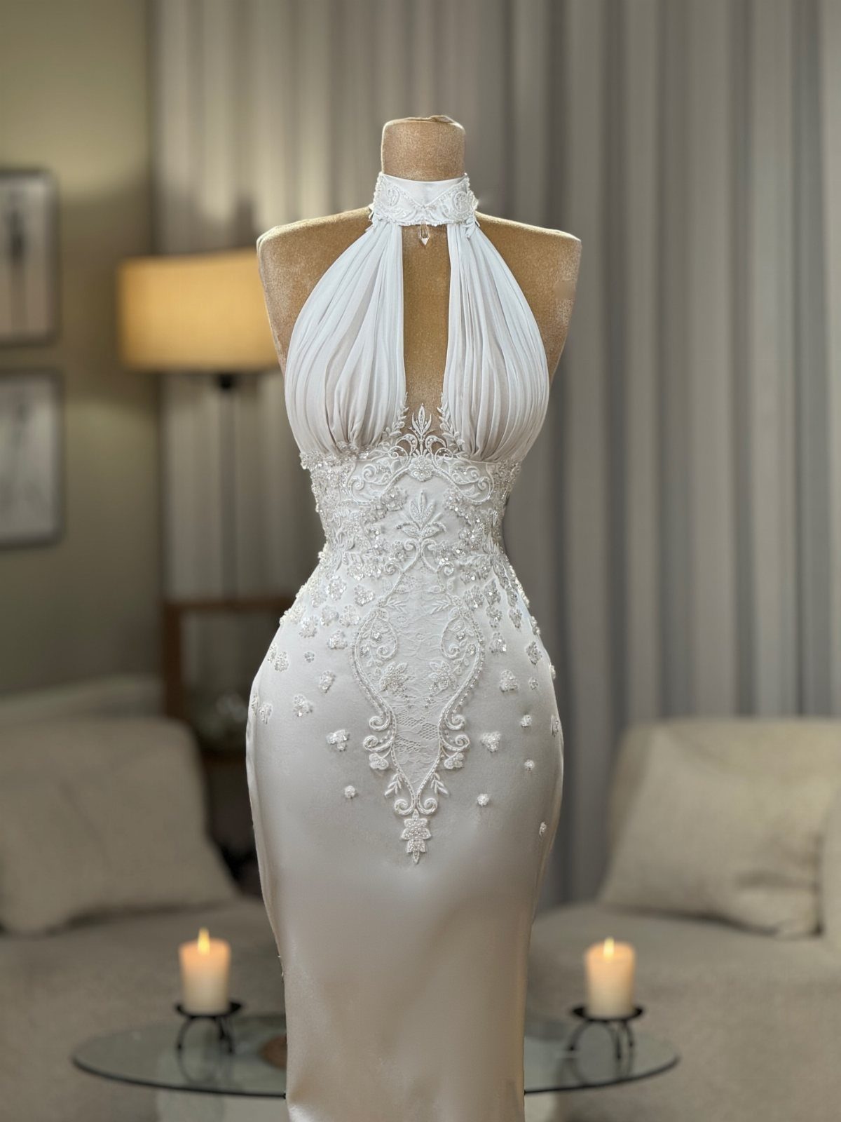 White halter-neck wedding dress with lace embroidery displayed on a mannequin.
