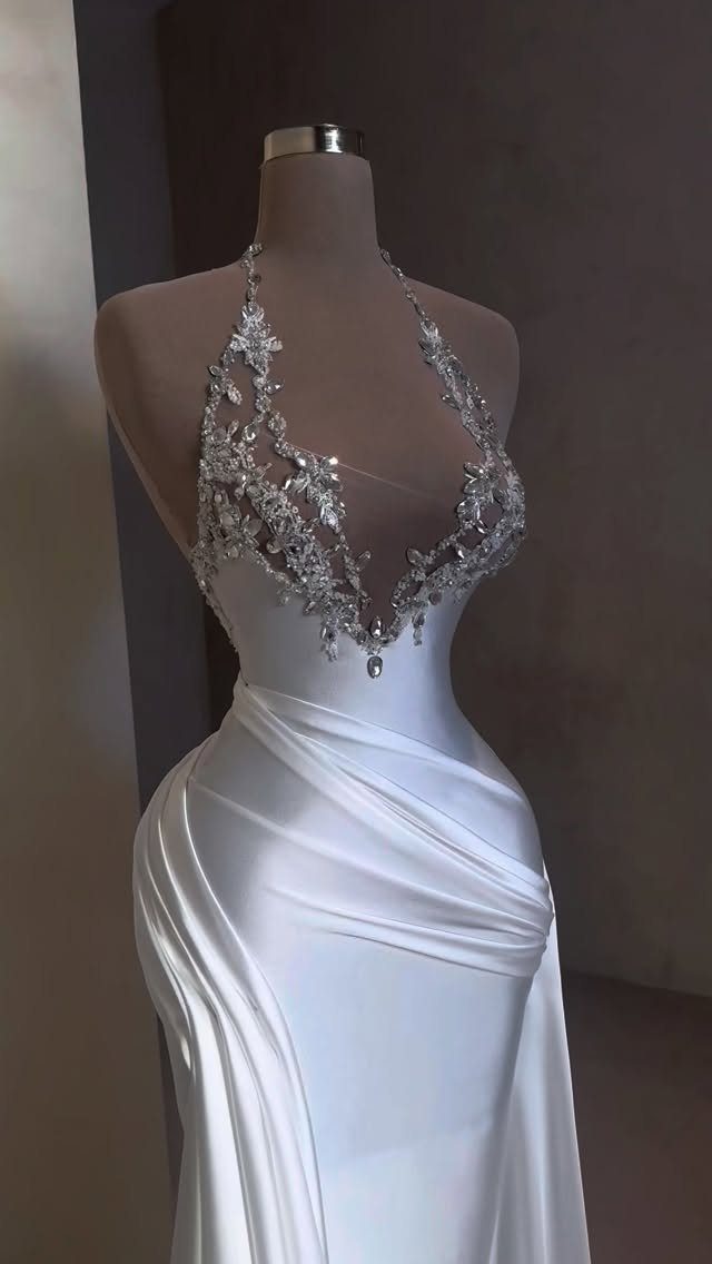 White satin wedding dress with a plunging V-neck halter neckline and crystal embellishments.