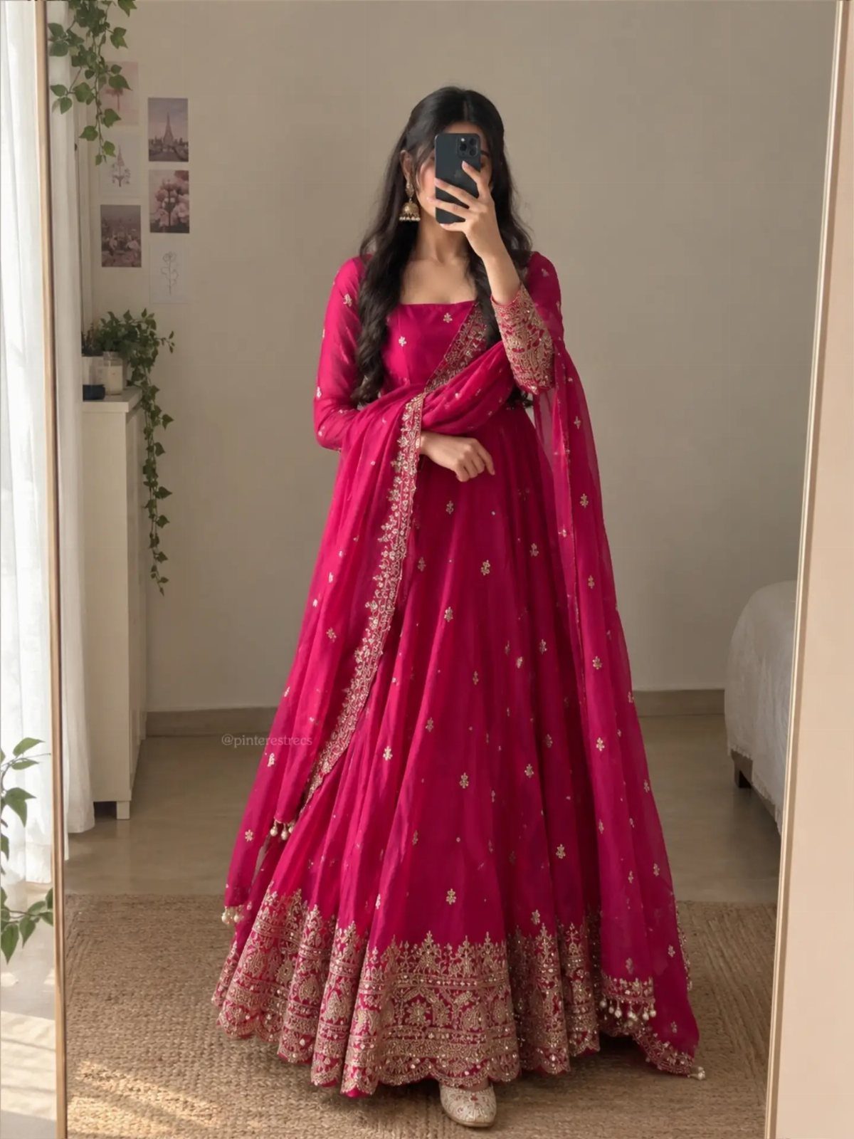 Woman in a magenta floor-length Anarkali suit with gold embroidery taking a mirror selfie.