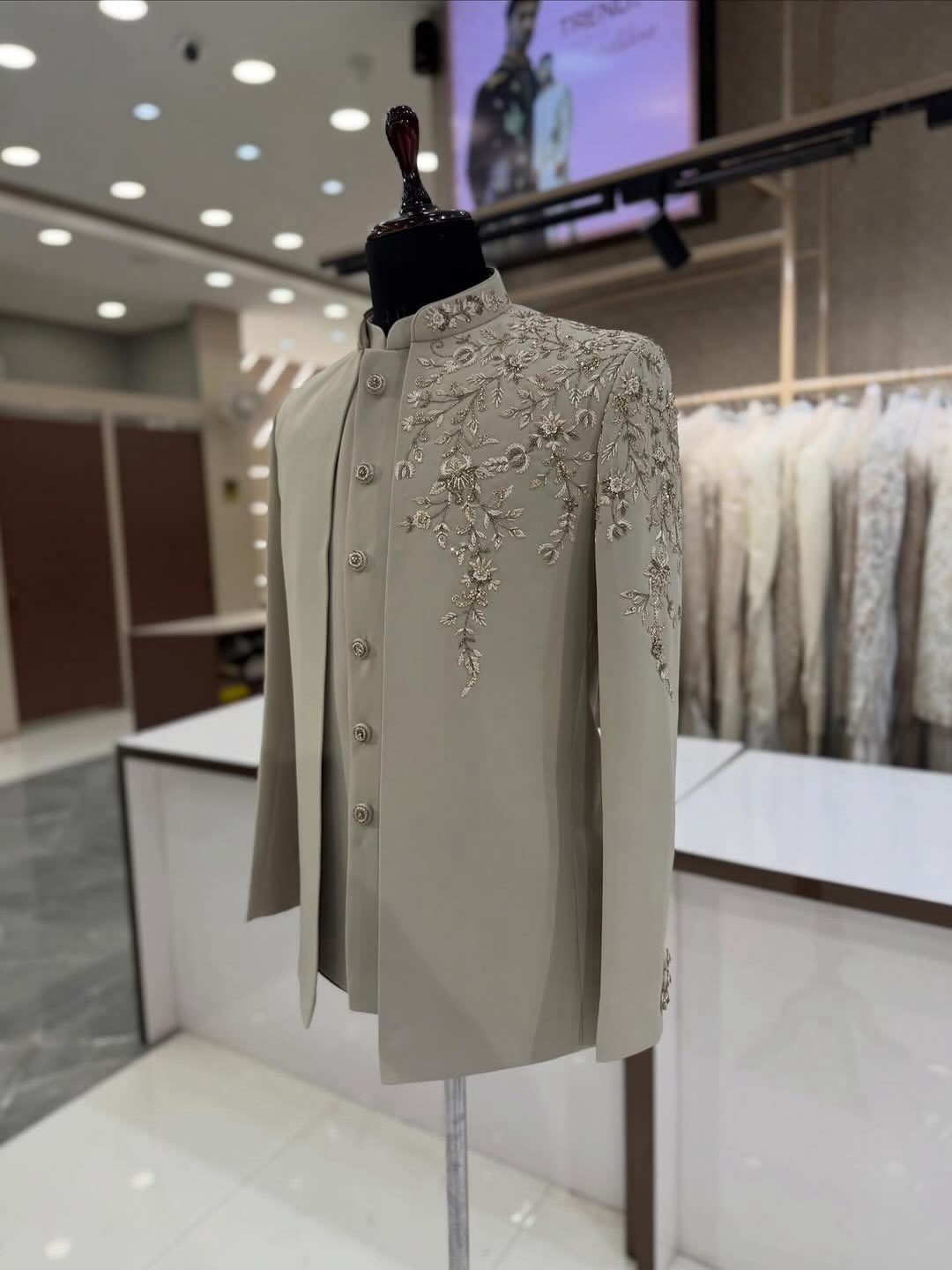 Sage green Bandhgala jacket with floral embroidery on a mannequin in a store