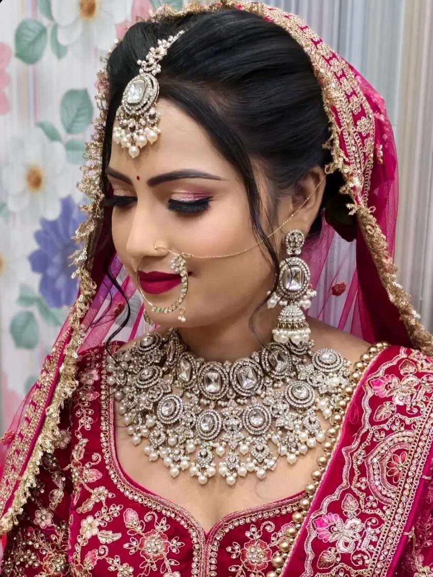Woman in red bridal attire wearing ornate silver and pearl bridal jewellery sets.