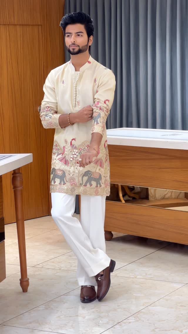 Man wearing a cream embroidered kurta and white trousers for an Indian wedding.