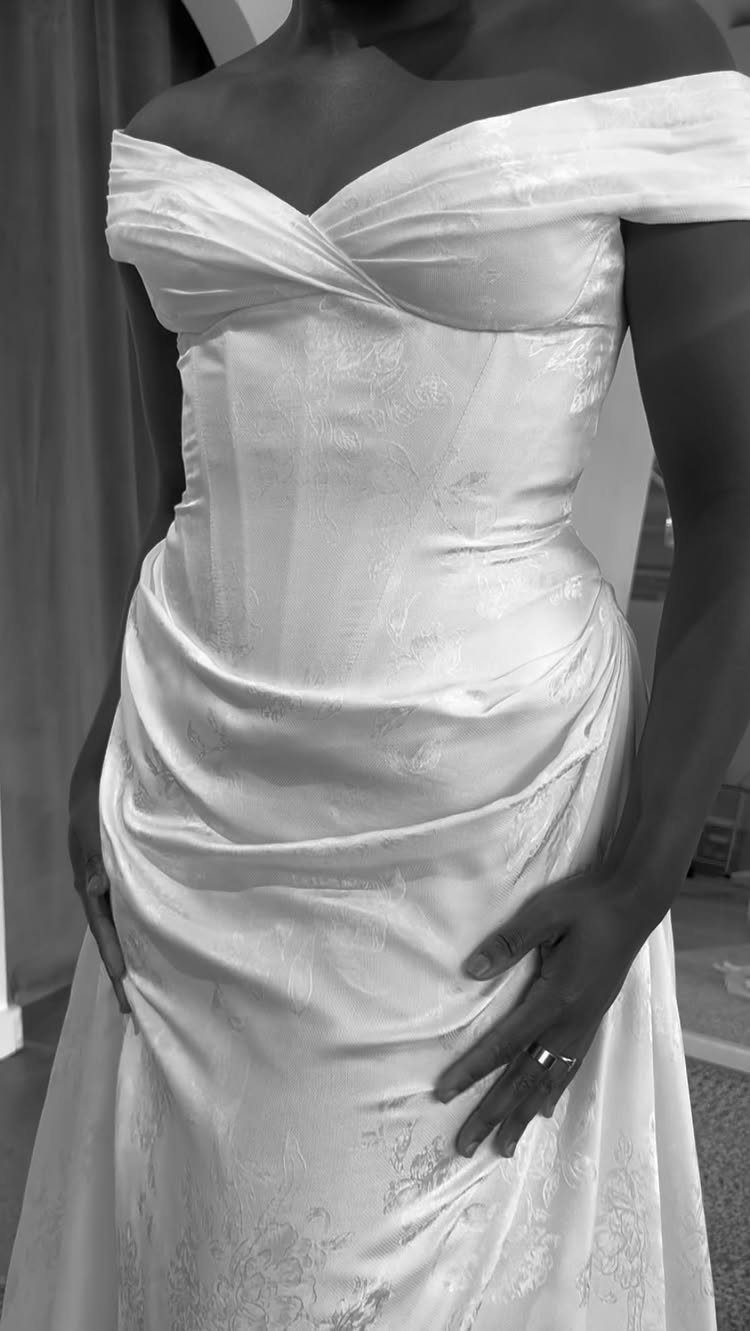 White jacquard wedding dress with off-the-shoulder neckline and subtle floral woven patterns.