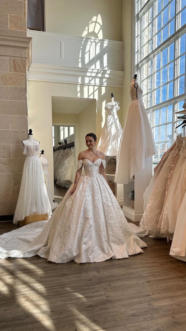 Woman in a white jacquard floral wedding dress posing in a bridal boutique