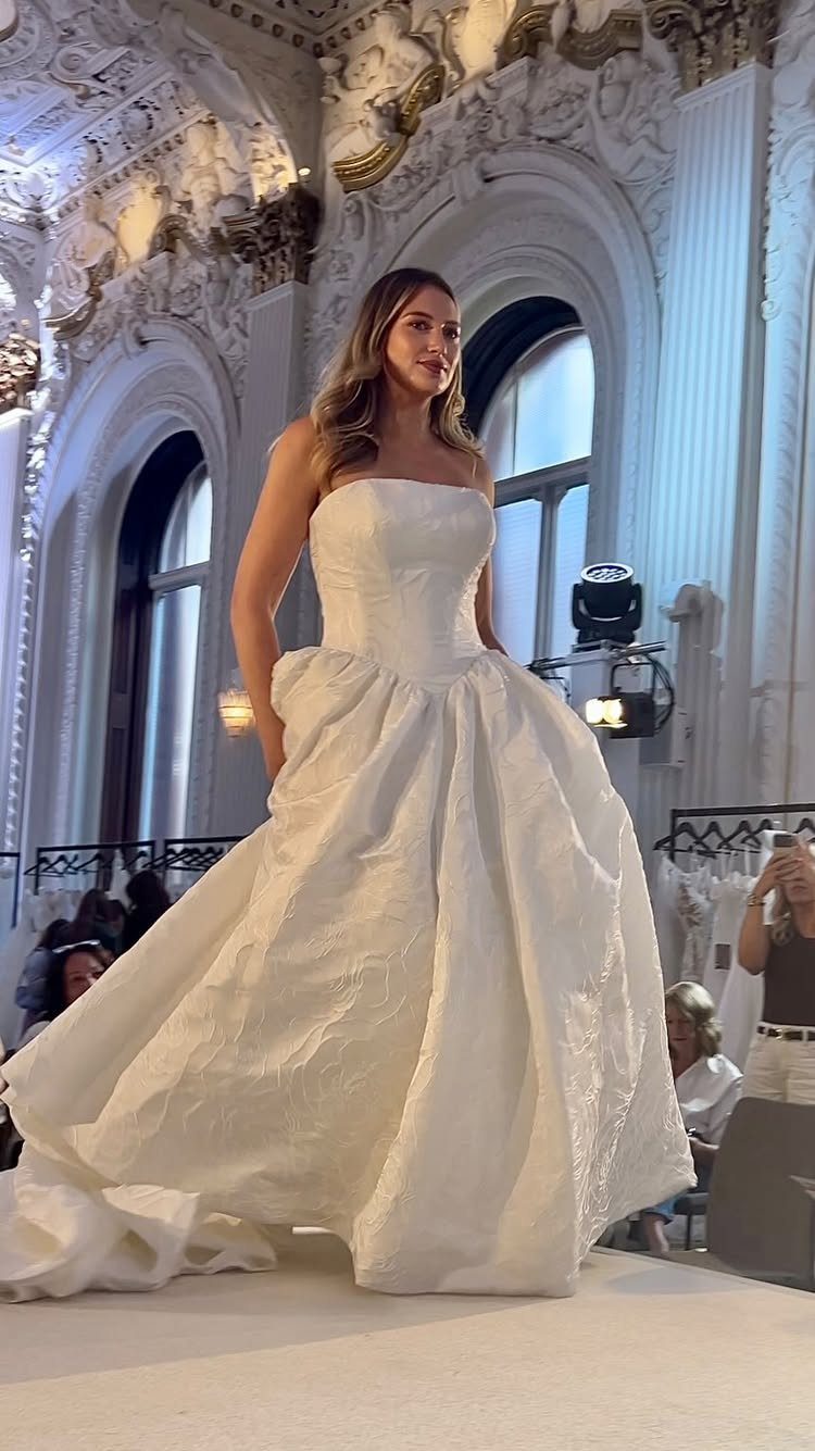 Woman in a strapless white jacquard wedding dress walking on a runway