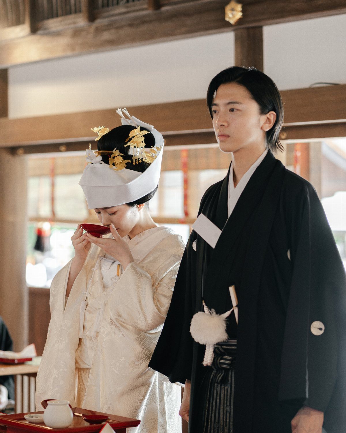 Japanese couple in traditional wedding attire performing a sake exchange ritual indoors