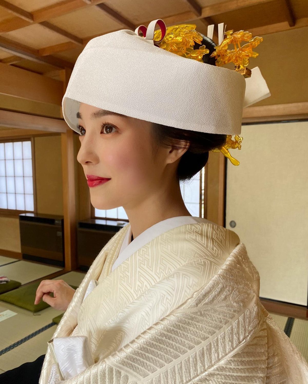 Woman wearing a white Shiromuku kimono and traditional headpiece in a Japanese room