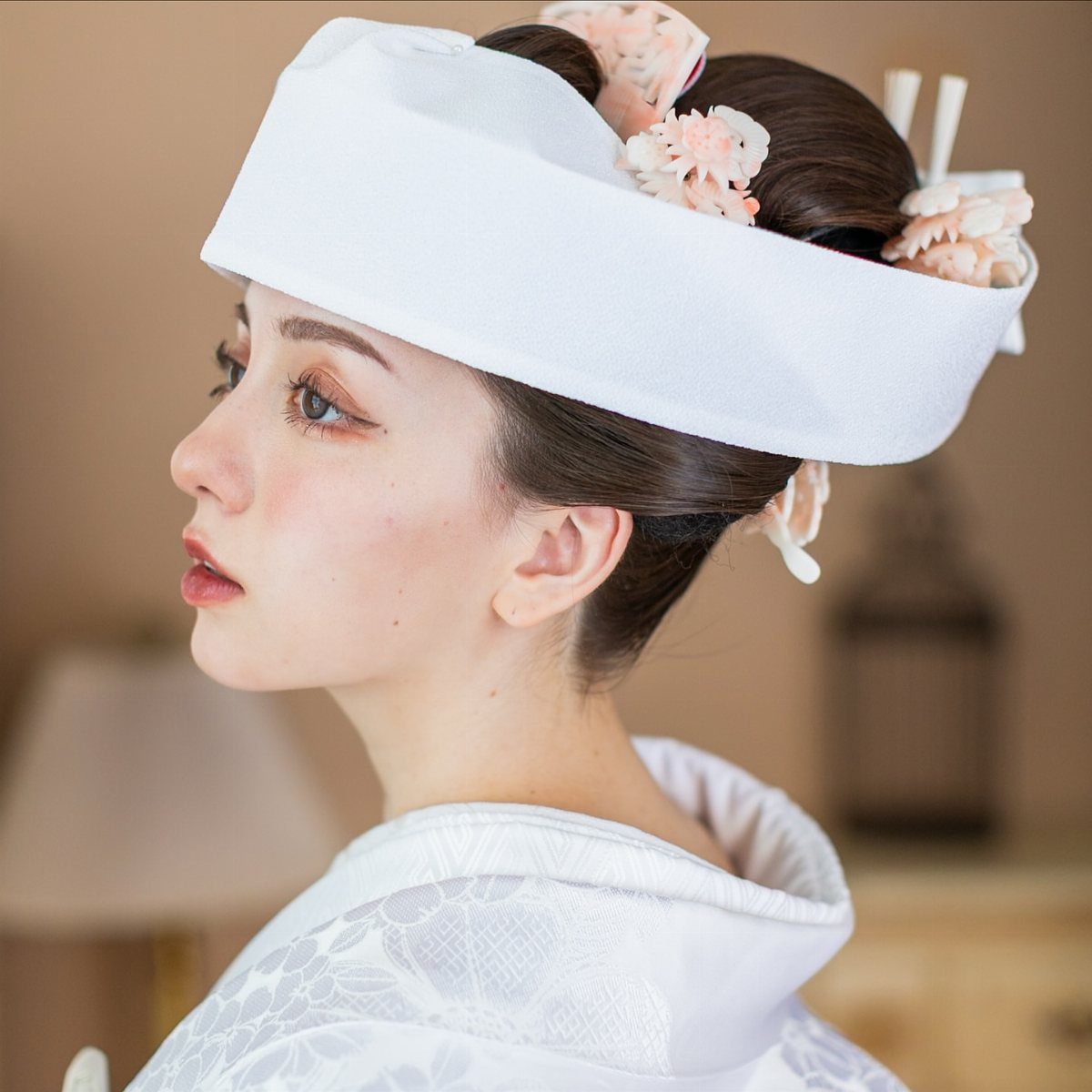 Japanese bride wearing a white tsunokakushi headpiece and traditional white wedding kimono.