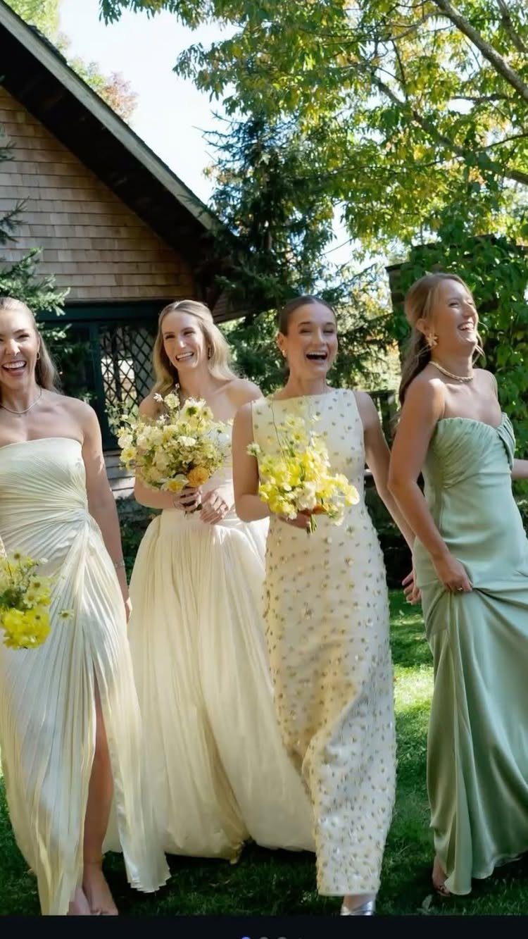 Four bridesmaids in mismatched pale yellow and sage green dresses holding yellow bouquets.