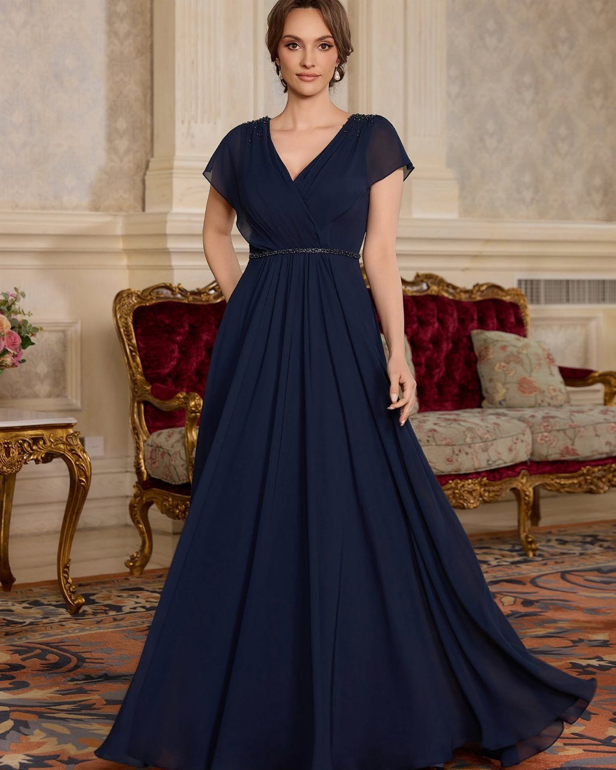 Woman in a navy blue floor-length gown with short sheer sleeves and beaded waist.