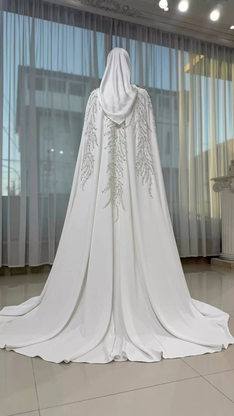White wedding gown with matching hijab and silver embroidered cape on a mannequin