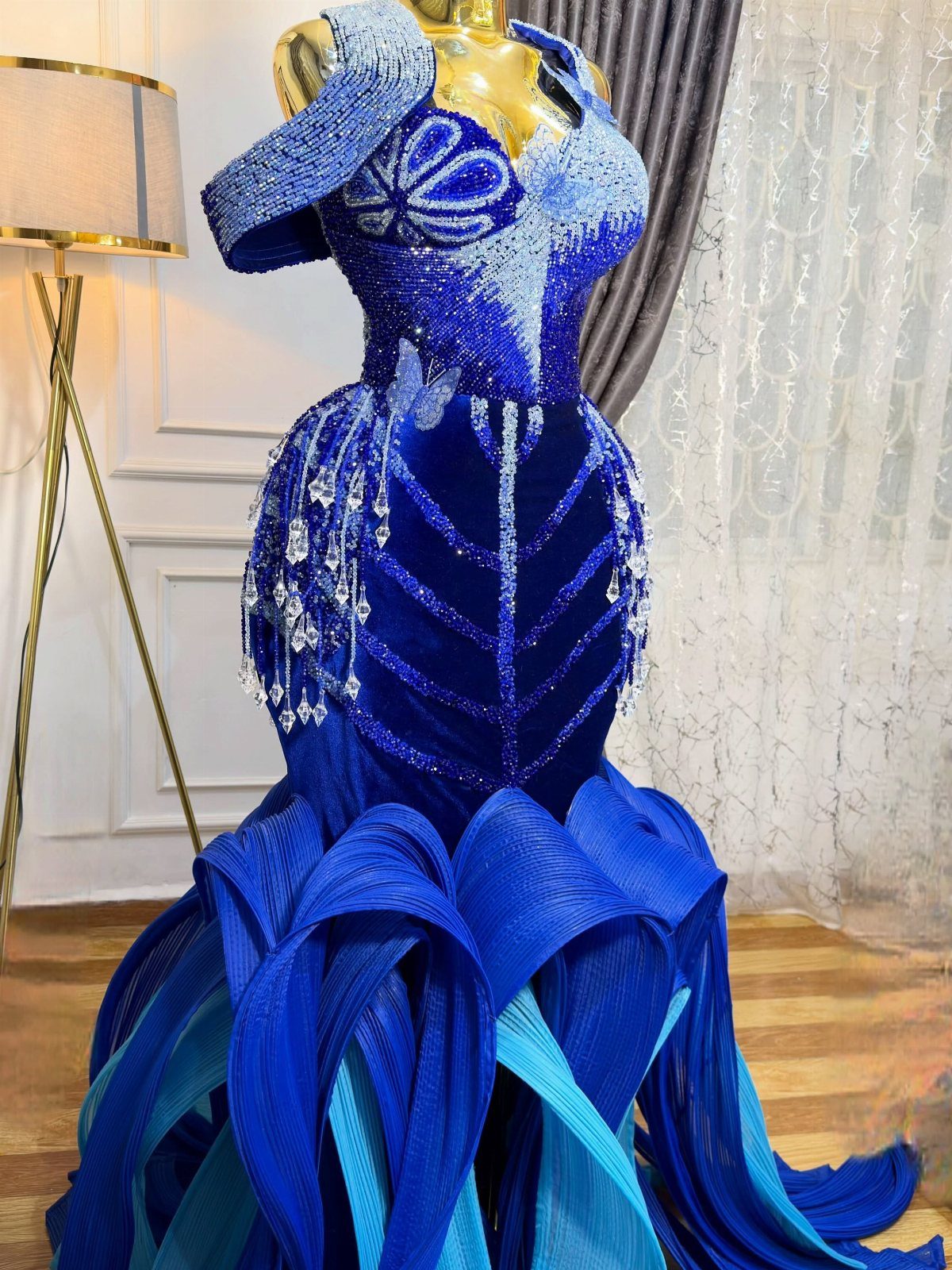 Royal blue mermaid gown with intricate beadwork and embroidery on a gold mannequin