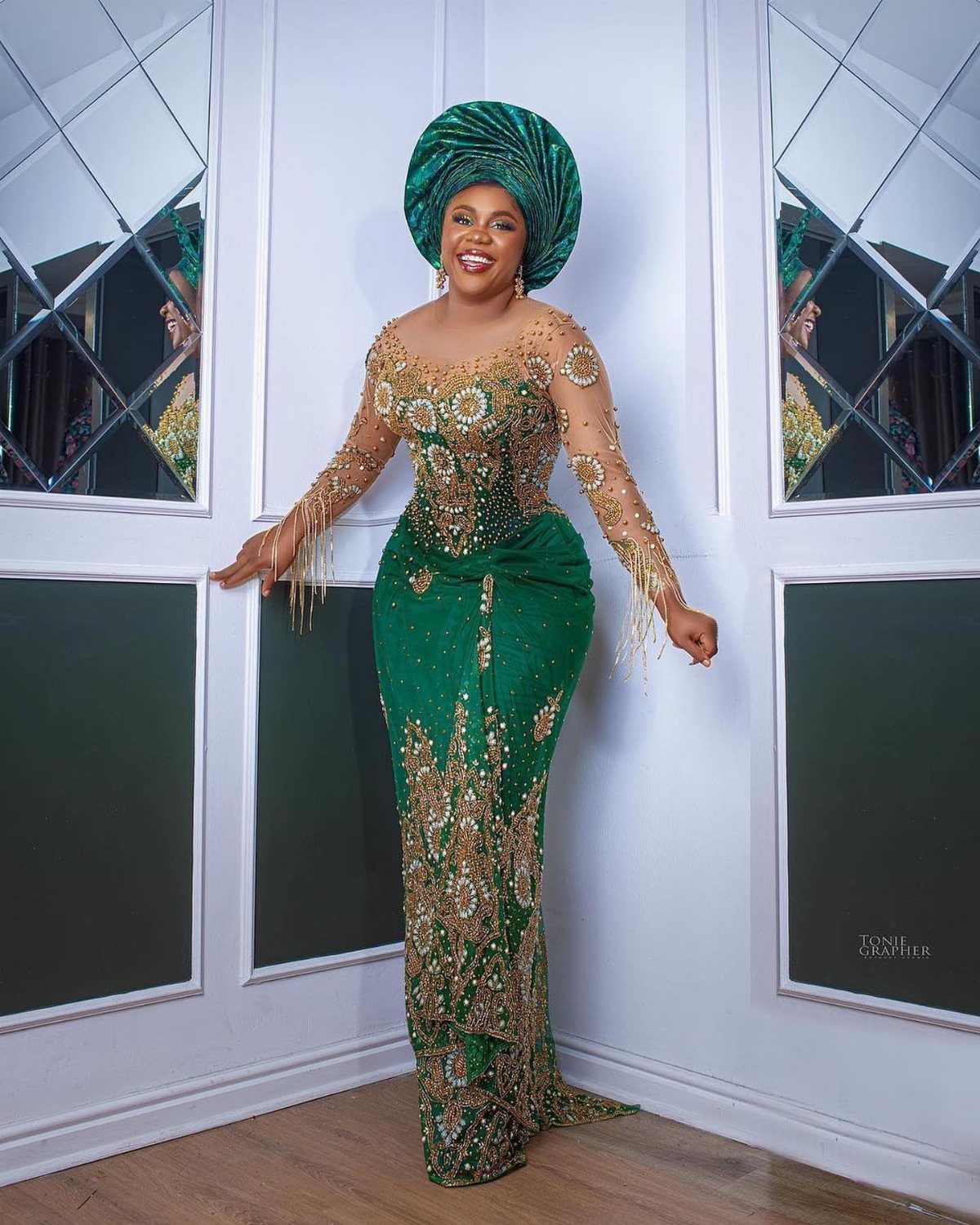 Woman in a green and gold Nigerian wedding dress with a matching gele headtie.