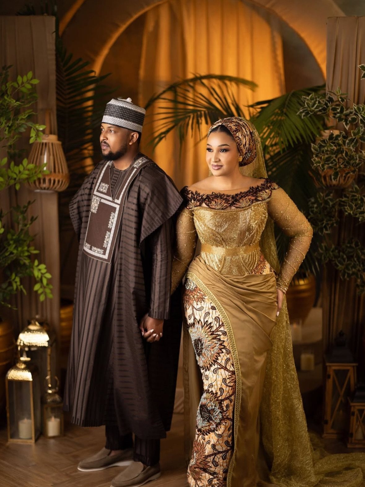 Couple in traditional Hausa bridal attire, woman in gold gown and man in agbada.