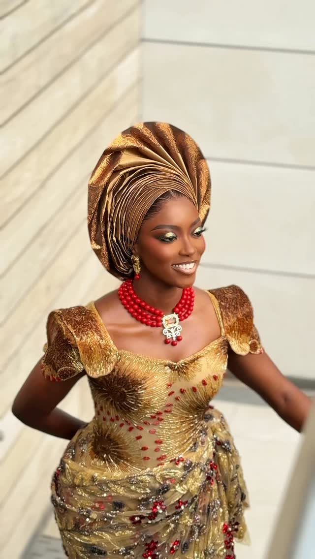Woman in gold traditional Igbo bridal attire with a red coral bead necklace.