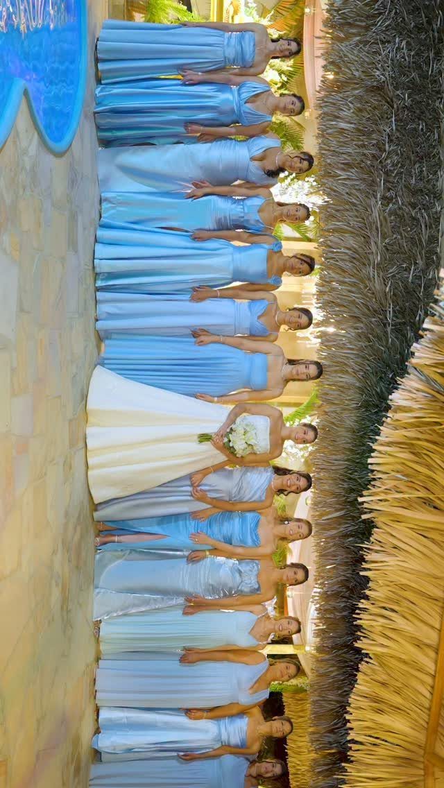 Bridesmaids in periwinkle blue chiffon dresses standing with a bride in white.