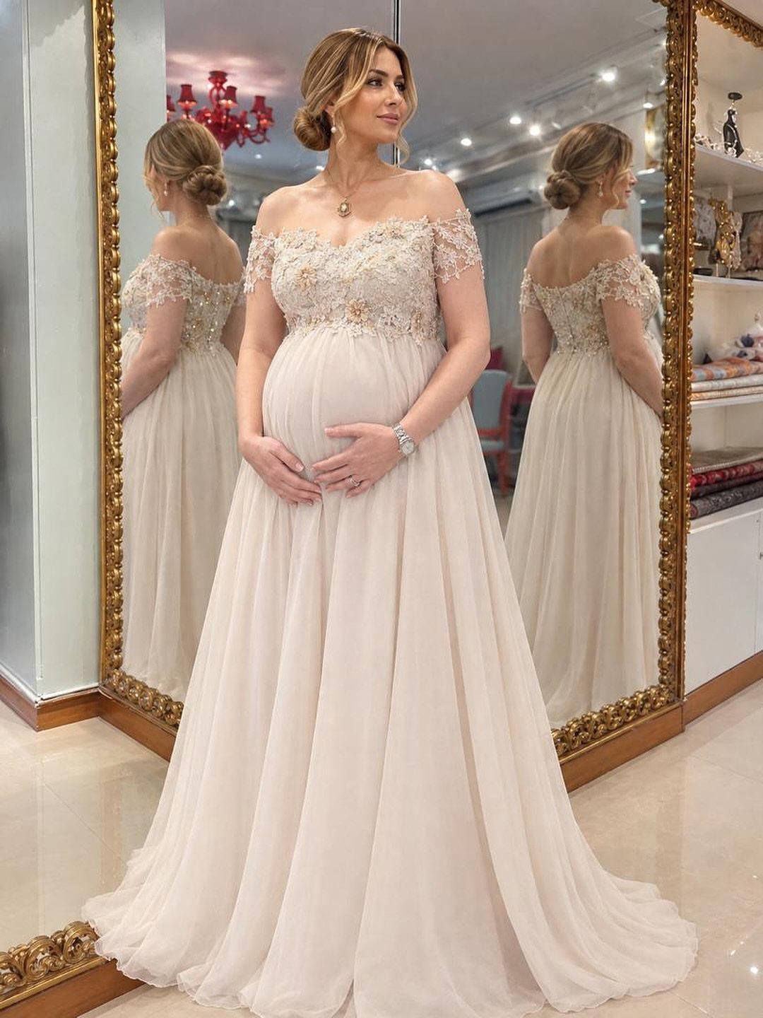 Pregnant woman in a cream chiffon wedding dress with lace bodice and flowing skirt.