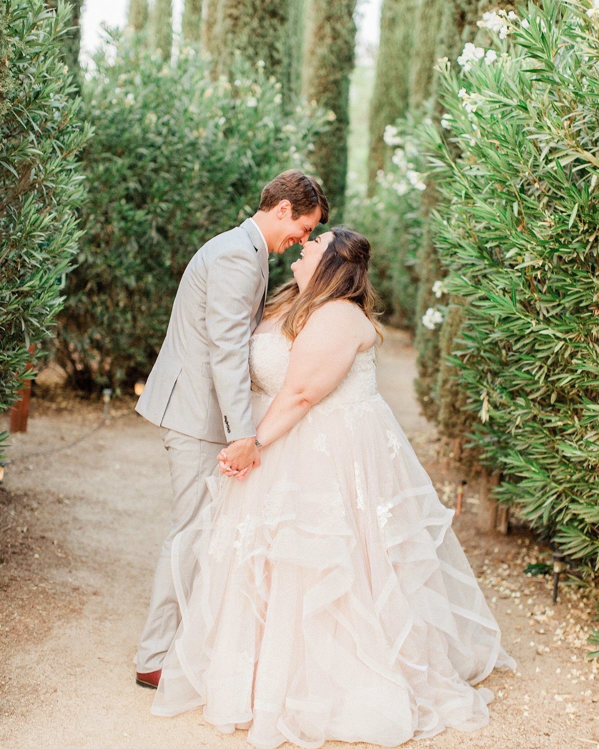 Pregnant woman in a ruffled pink wedding dress and man in grey suit.