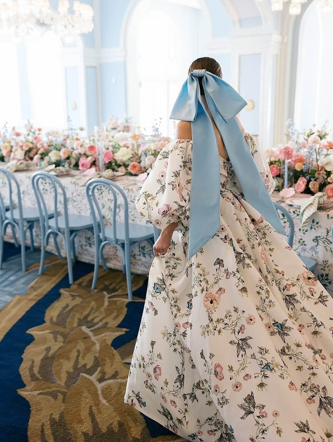Woman in a floral print wedding gown with a large light blue bow.