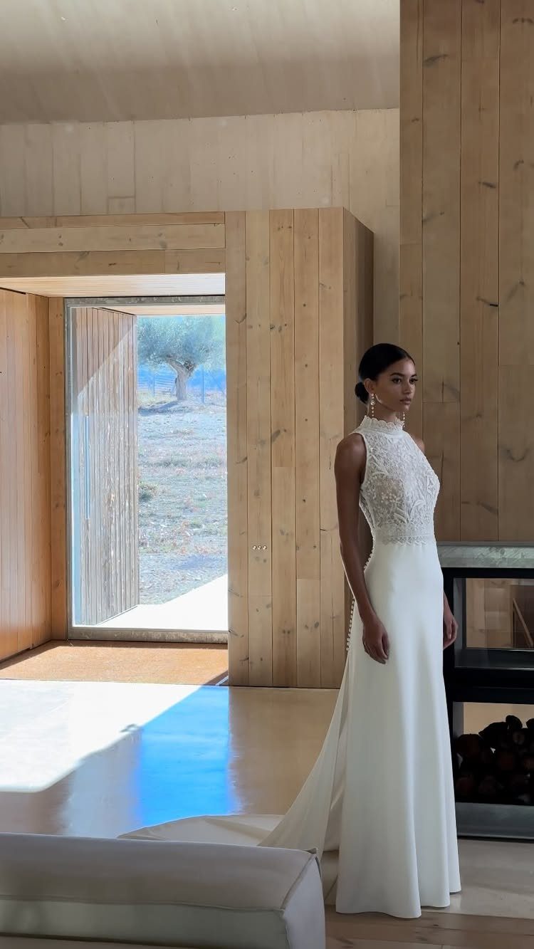 Woman in a white lace halter wedding dress standing in a wooden room.